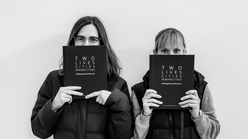 photo of two female photographers holding their joint project - a photo book about their shared but seperate perspectives.