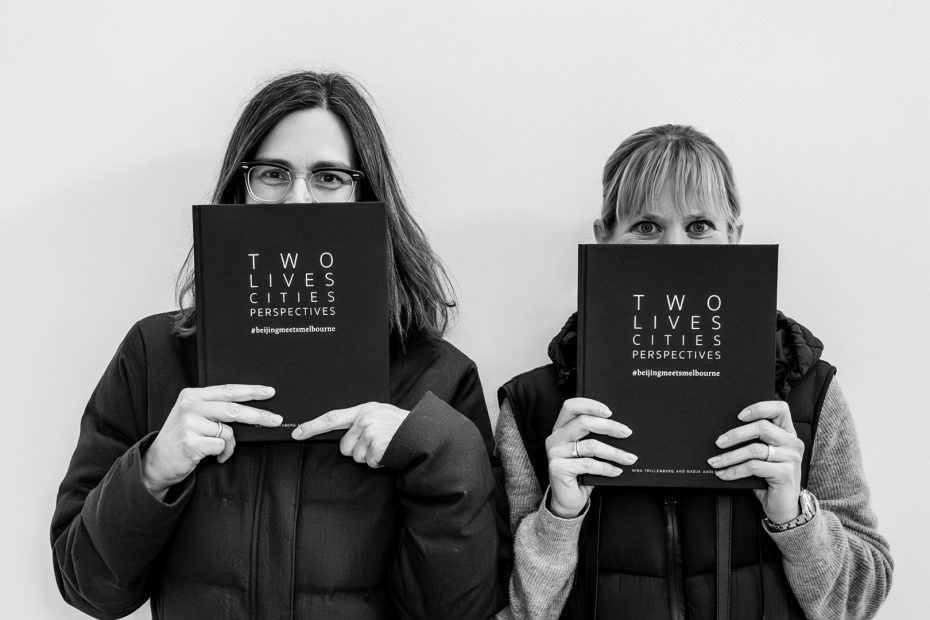 photo of two female photographers holding their joint project - a photo book about their shared but seperate perspectives.